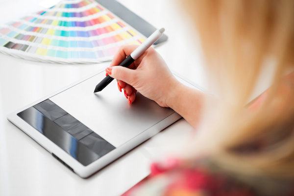 Graphic designer working on a digital tablet and with pantone palette designs for nameplates